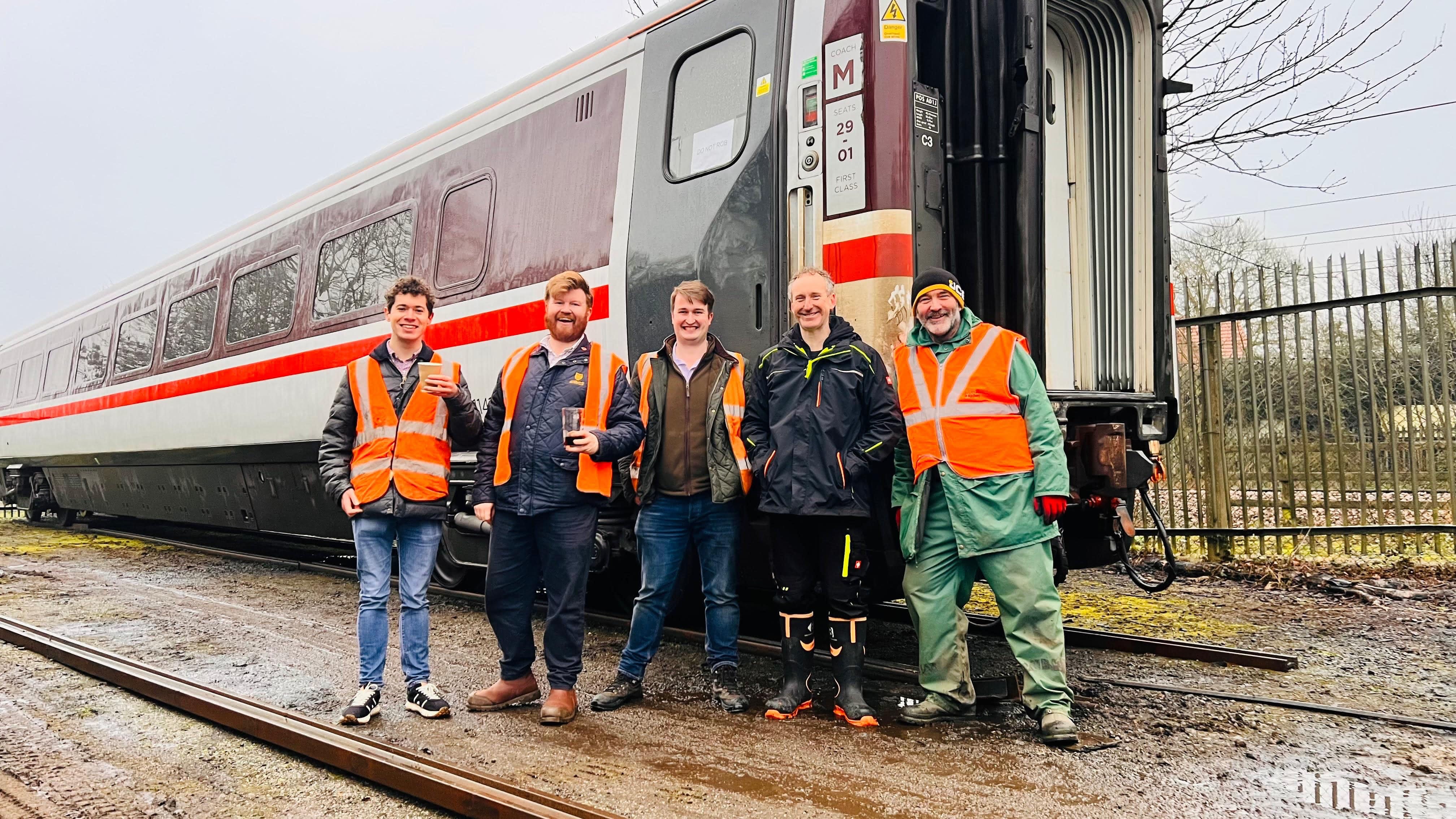 The 225 Preservation team stand next to newly preserved coach 11412